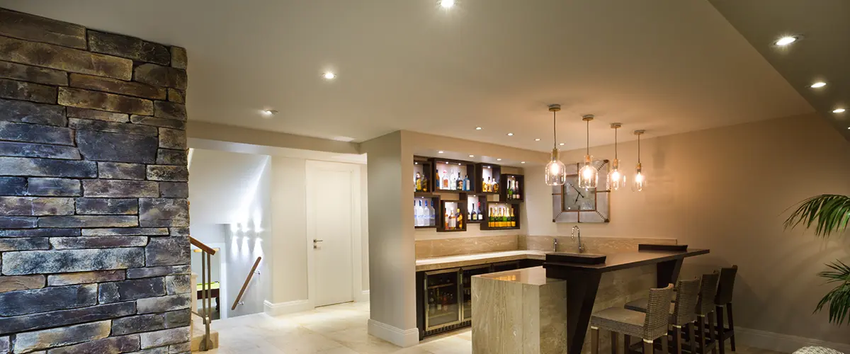 Contemporary basement bar with stone accent wall and hanging lights for a cozy entertainment space.