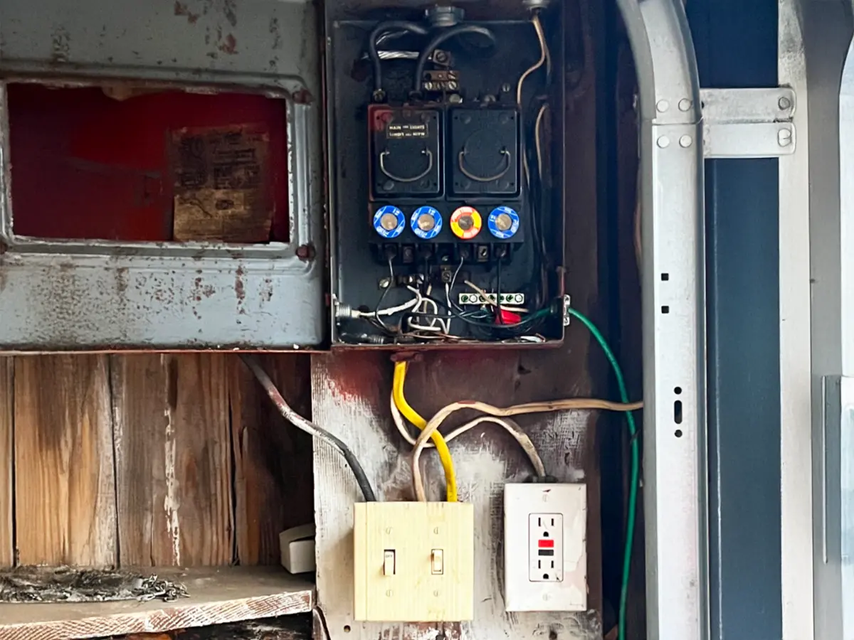 Old, exposed electrical panel with visible wiring before Tesla charger installation.