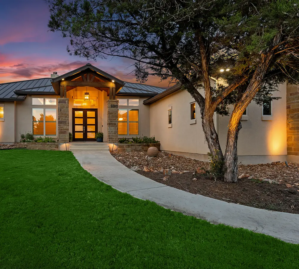 Residential home exterior with landscape lighting at sunset.