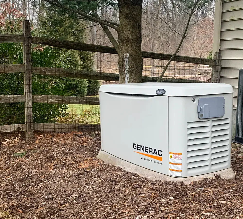 Generac Guardian Series home standby generator installed near a backyard fence.