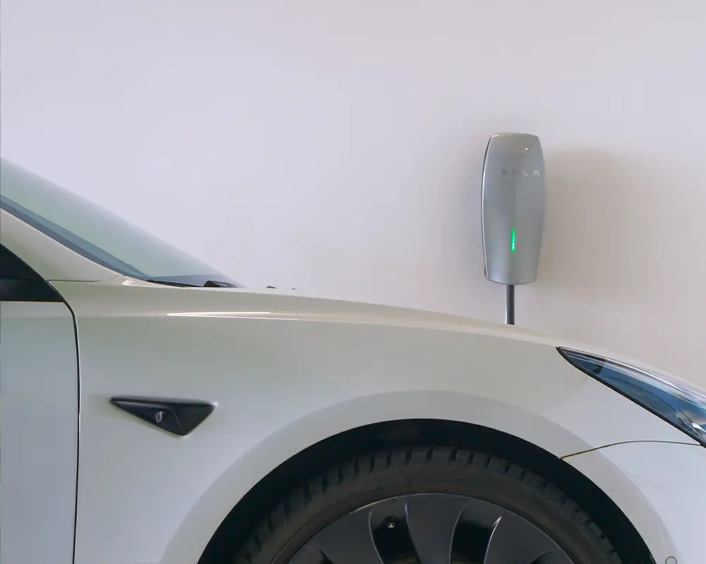 Tesla Model S charging in garage with wall-mounted Tesla charger, showing clean setup.