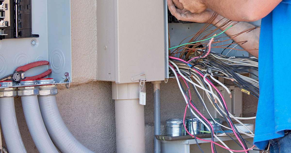 Electrician-repairing-outdoor-electrical-panel-with-multiple-wiring-connections