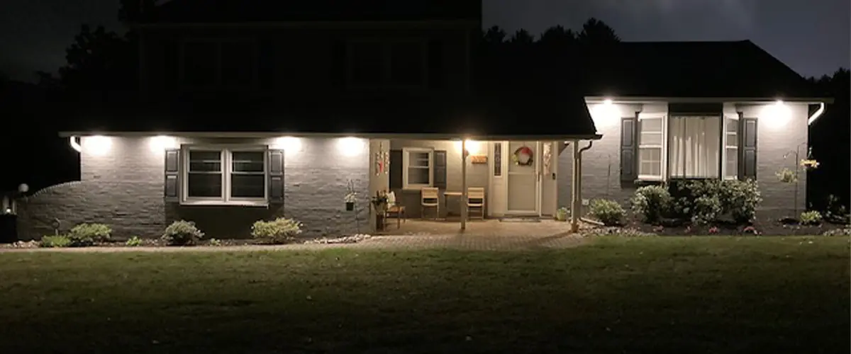 Exterior house with professional outdoor lighting at night, showcasing illuminated front facade and landscaping.