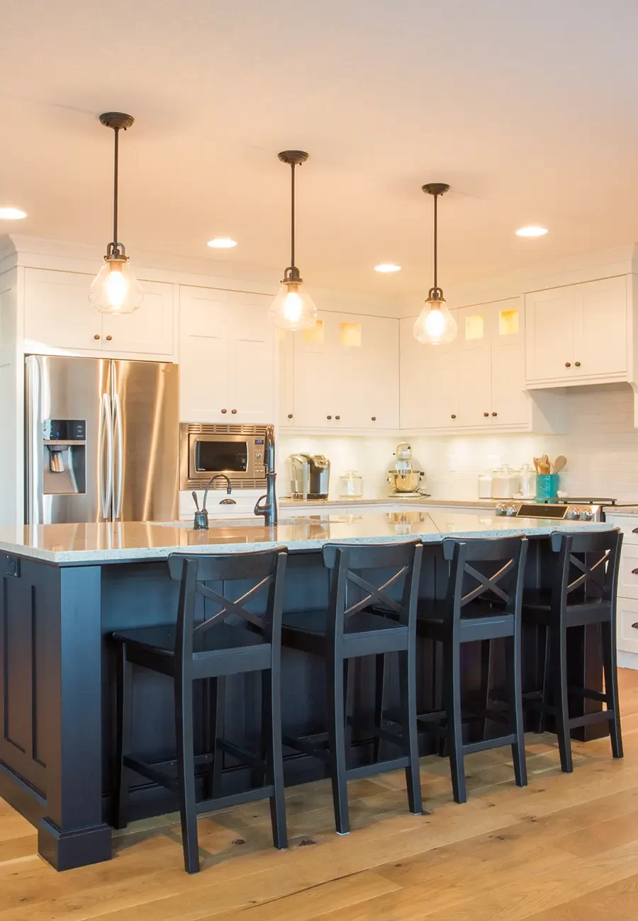 Modern kitchen lighting setup featuring pendant lights over island and recessed ceiling lights, enhancing ambiance and functionality.